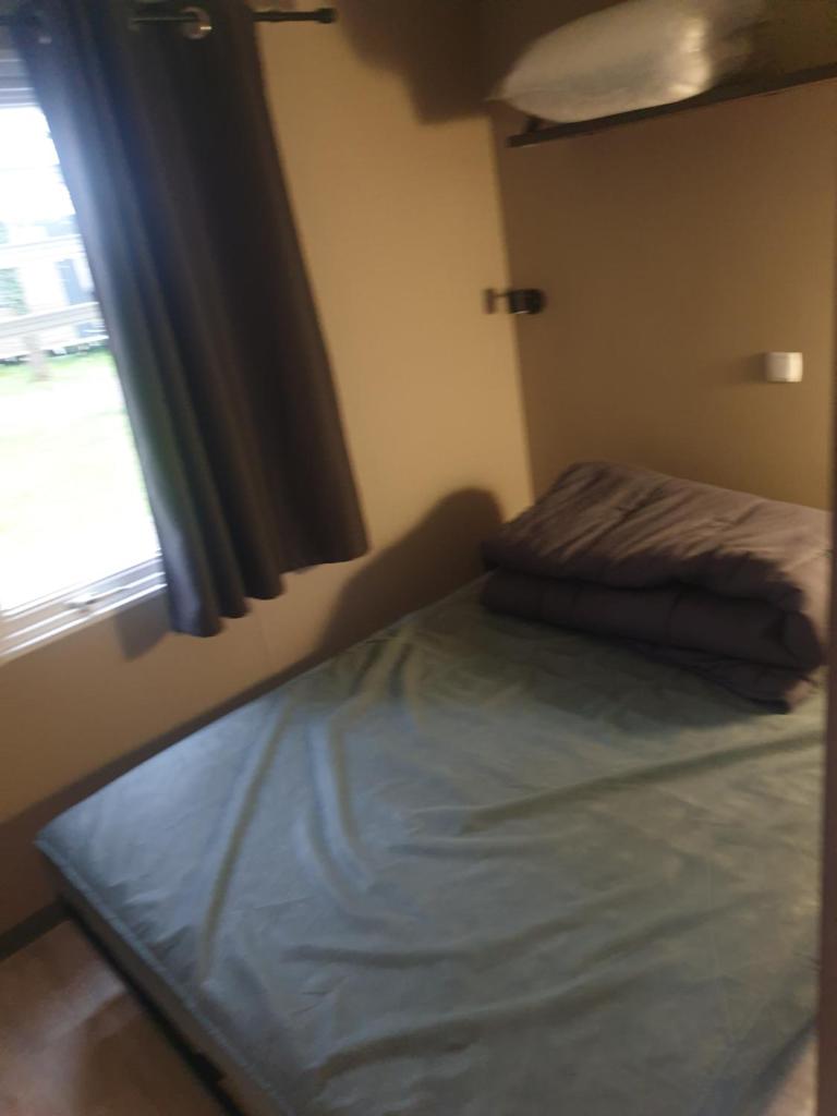un lit dans une chambre avec une fenêtre dans l'établissement Mobilhome proche Puy duFou, à La Boissière-de-Montaigu