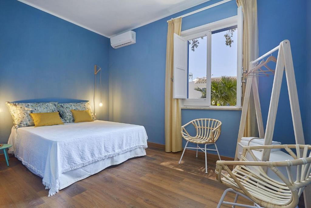 une chambre bleue avec un lit et une fenêtre dans l'établissement Villa Maraus by PosarelliVillas, à Marausa