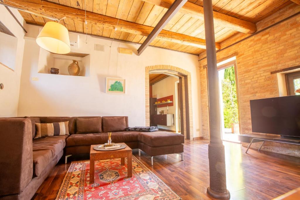 un salon avec un canapé et une télévision dans l'établissement Villa Gelso - Tenuta esclusiva con piscina, sauna e vista panoramica, à Belvedere Ostrense