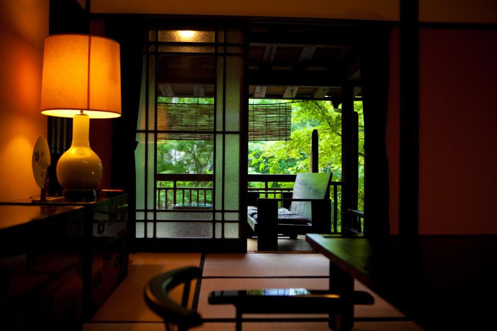 un salon avec une lampe et une table avec une chaise dans l'établissement Hatago Kayausagi, à Hita