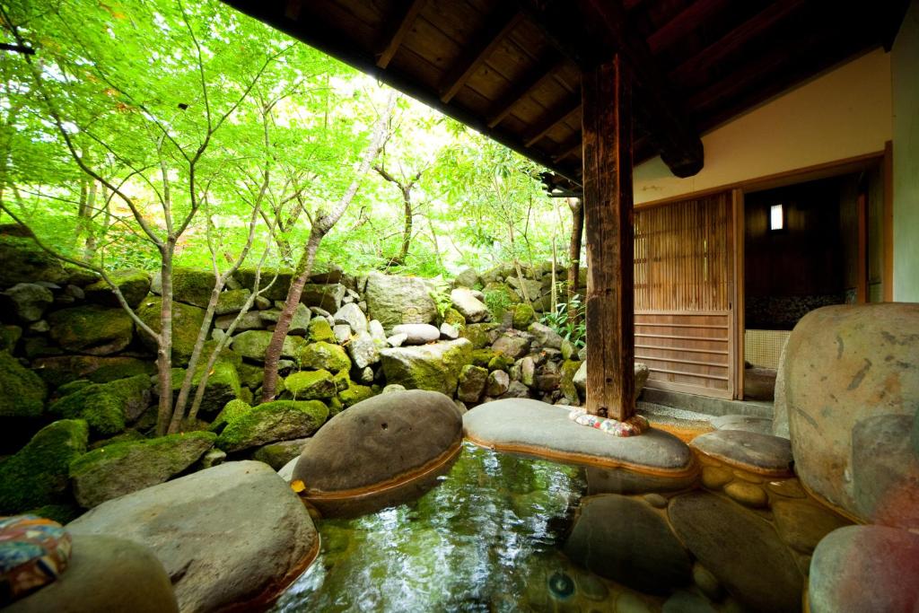 une chambre avec un ruisseau avec des rochers et une maison dans l'établissement Hatago Kayausagi, à Hita