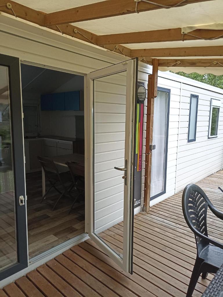 une porte coulissante en verre sur une terrasse avec une table dans l'établissement Mobil Home 6 personnes de 41m2 dans camping 4 étoiles, à Bidart