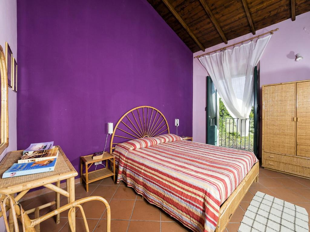 - une chambre avec des murs violets, un lit et une table dans l'établissement Villa Idyllica, à Gaggi