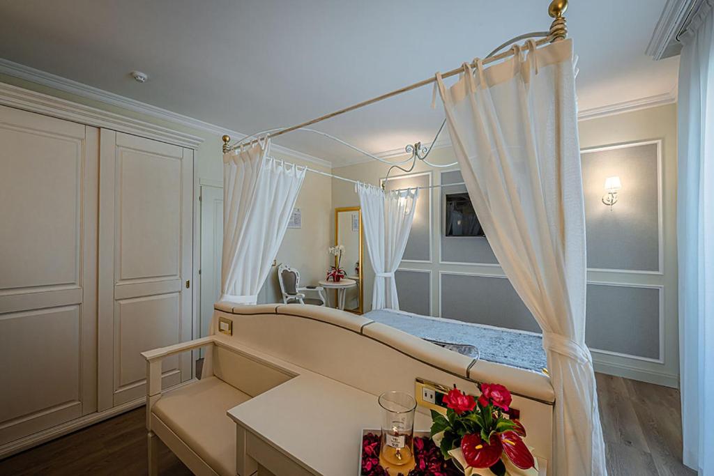 une chambre avec un lit à baldaquin avec des fleurs sur une table dans l'établissement Hotel Ca' D'Oro Tre Stelle Superior Adults only, à Bibione
