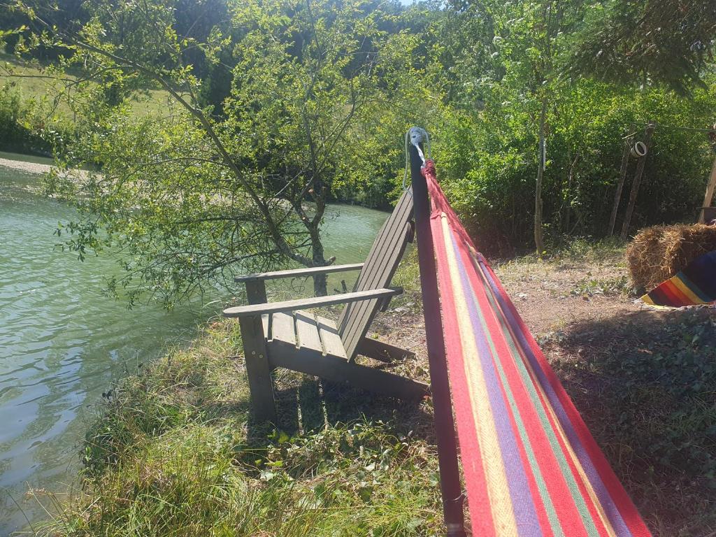 un banc de parc à côté d'une rivière avec un arc-en-ciel dans l'établissement tipi des sioux, à Moulayrès
