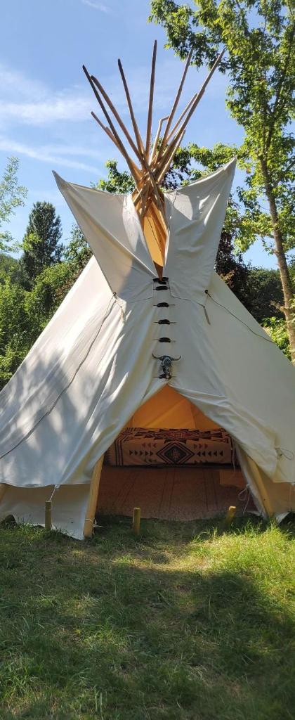une grande tente blanche dans l'herbe dans un champ dans l'établissement tipi des sioux, à Moulayrès