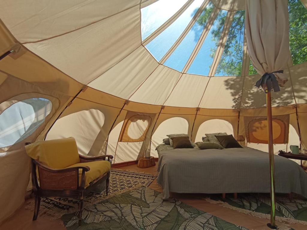- une chambre dans une tente avec un lit et une chaise dans l'établissement ECO CEIBA, à Busque
