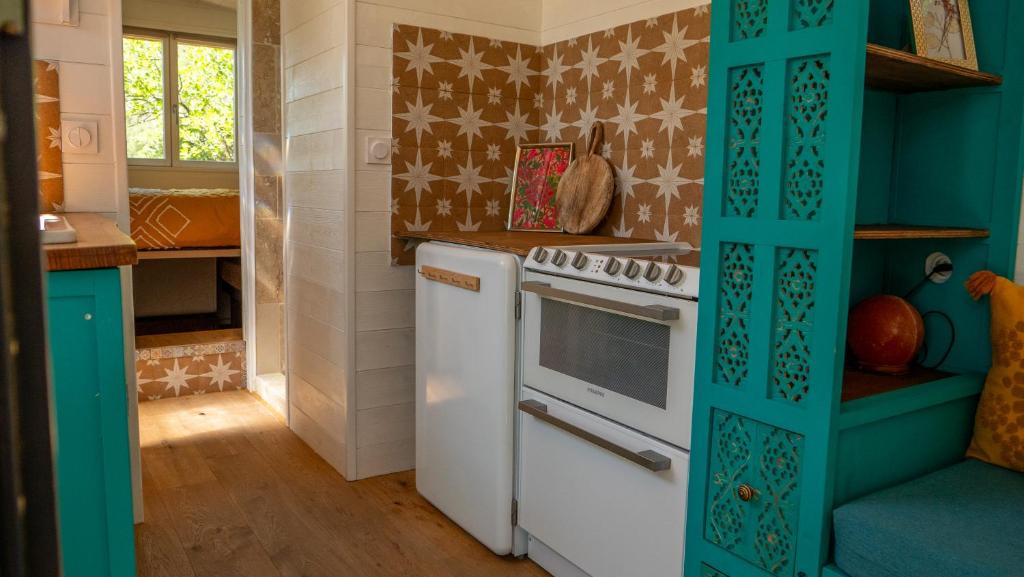 Il comprend une cuisine dotée d'une cuisinière blanche et d'un mur bleu. dans l'établissement Les Cabanes d'ErbeFol, à Ansignan 37 autres photos
