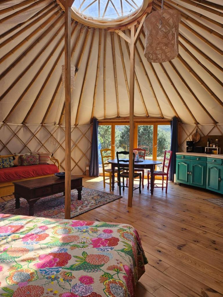 une chambre dans une yourte avec une table et des chaises dans l'établissement Les Cabanes d'ErbeFol, à Ansignan
