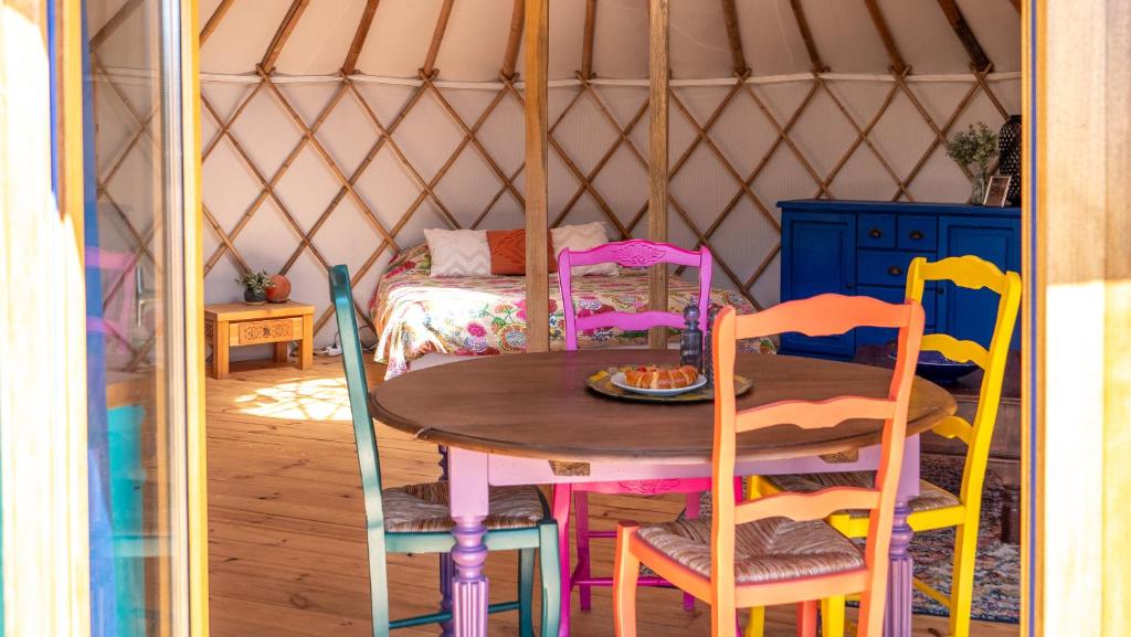 - une chambre avec une table et des chaises dans une yourte dans l'établissement Les Cabanes d'ErbeFol, à Ansignan