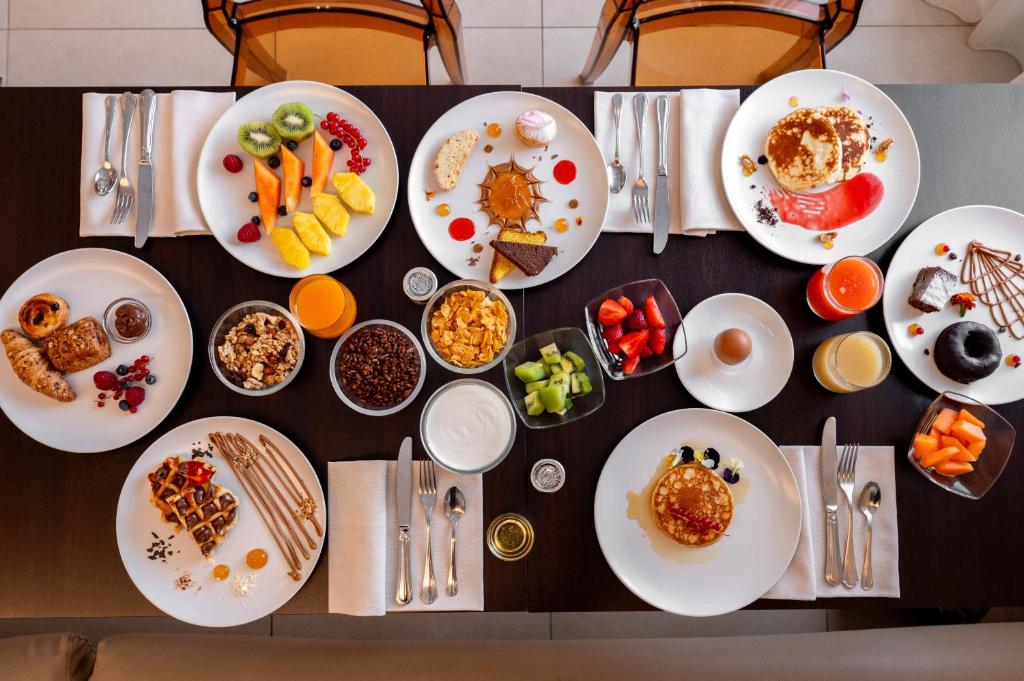 une table avec des assiettes de petit-déjeuner dessus dans l'établissement Bellettini Hotel, à Milano Marittima