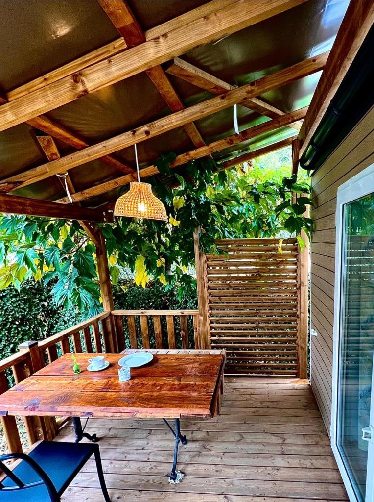 une table en bois sur une terrasse avec un plafond dans l'établissement LES BASTIDES DE CHANTERAINE Bungalows, Lodges & Spa, à Aiguines