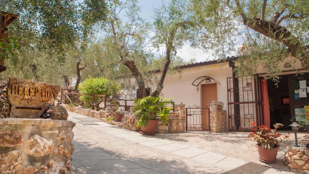 un bâtiment avec des arbres et des plantes en pot devant lui dans l'établissement Zagare Residence, à Rodi Garganico