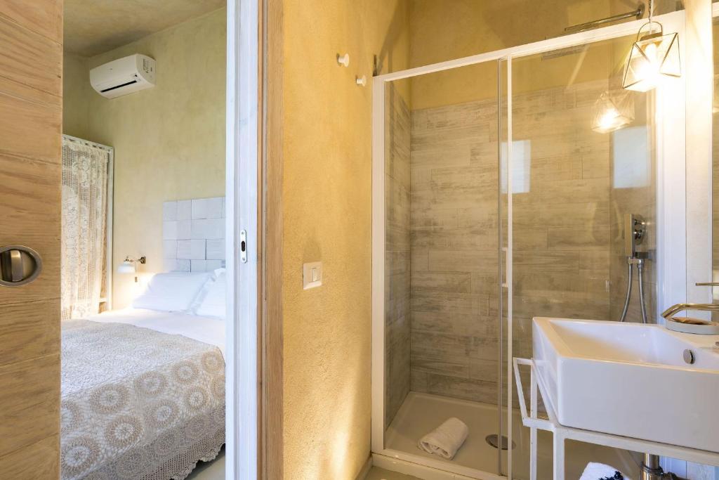 une salle de bain avec une douche et un lavabo et un lit dans l'établissement Villa Madera, à Caltagirone