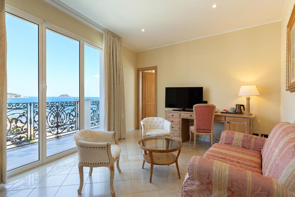 un salon avec un canapé et une table avec des chaises dans l'établissement Grand Hotel Mediterranee, à Alassio