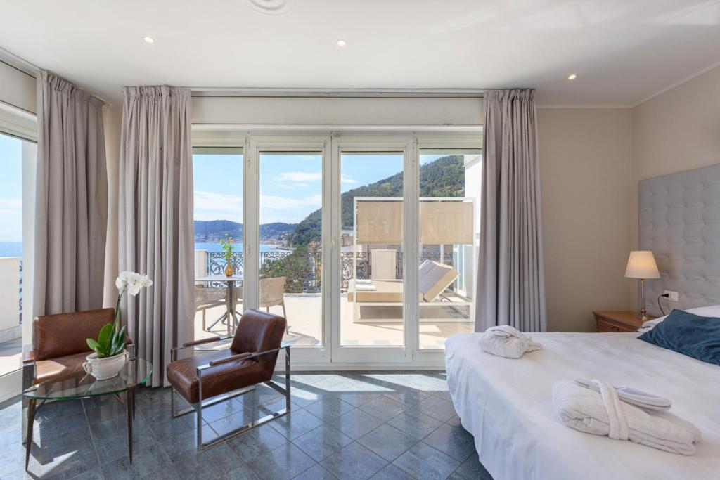 une chambre avec un lit et une chaise et un balcon dans l'établissement Grand Hotel Mediterranee, à Alassio 105 autres photos
