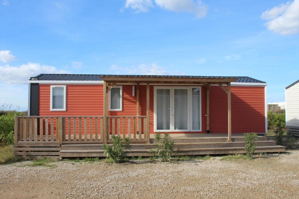 une petite maison rouge avec une véranda et une véranda dans l'établissement Camping La Brise de Camargue, à Saintes-Maries-de-la-Mer