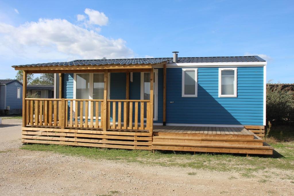 une petite maison bleue avec une terrasse en bois dans l'établissement Camping La Brise de Camargue, à Saintes-Maries-de-la-Mer