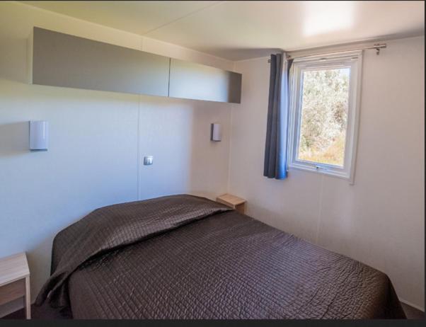 une chambre avec un lit et une fenêtre dans l'établissement Camping La Brise de Camargue, à Saintes-Maries-de-la-Mer