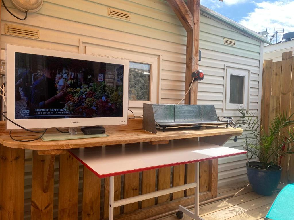 une télévision sur une table en bois sur une terrasse dans l'établissement Mobil home de charme à la mer, à Fréjus