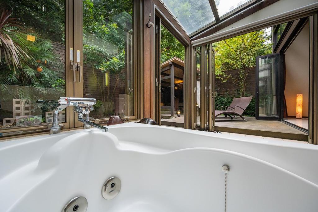 La salle de bains est pourvue d'une baignoire en face d'une fenêtre. dans l'établissement Mori no Nanakusa, à Munakata