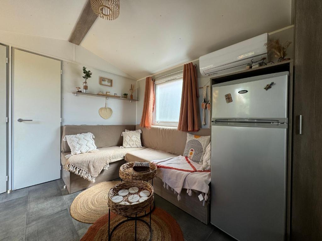Cette petite chambre dispose d'un canapé et d'un réfrigérateur. dans l'établissement Mobil home climatisé golf de saint tropez camping 4 étoile, à Gassin