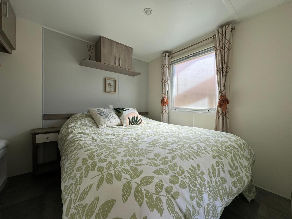 - une chambre avec un lit doté d'une couette verte et d'une fenêtre dans l'établissement Mobil home climatisé golf de saint tropez camping 4 étoile, à Gassin
