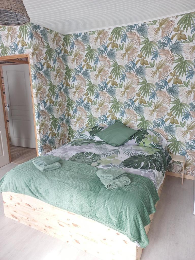 - un lit avec une couette verte et un mur dans l'établissement Gîte Germaine et Yves, à Fix-Saint-Geneys