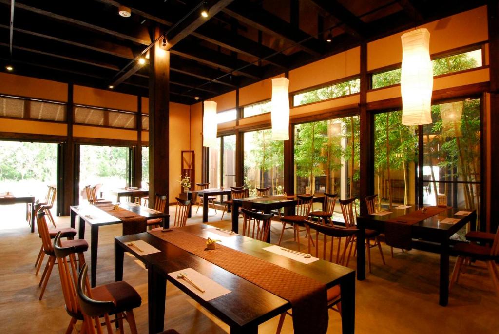 un restaurant avec des tables et des chaises en bois et des fenêtres dans l'établissement Mori no Nanakusa, à Munakata
