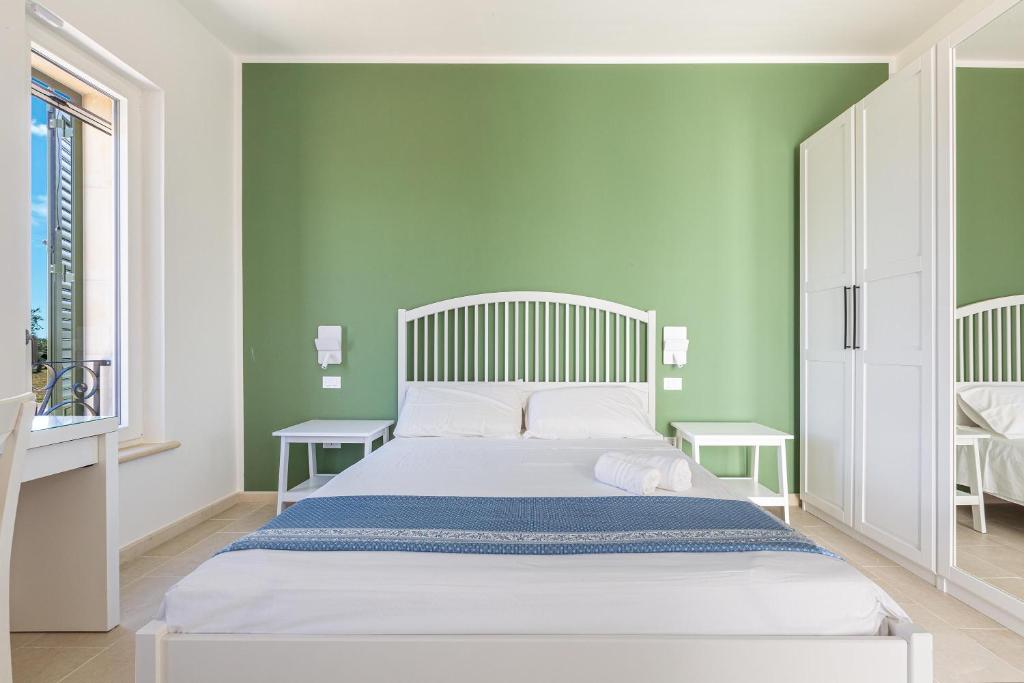 une chambre avec un lit blanc et des murs verts dans l'établissement Villa Cesira by Perle di Puglia, à Muro Leccese 54 autres photos