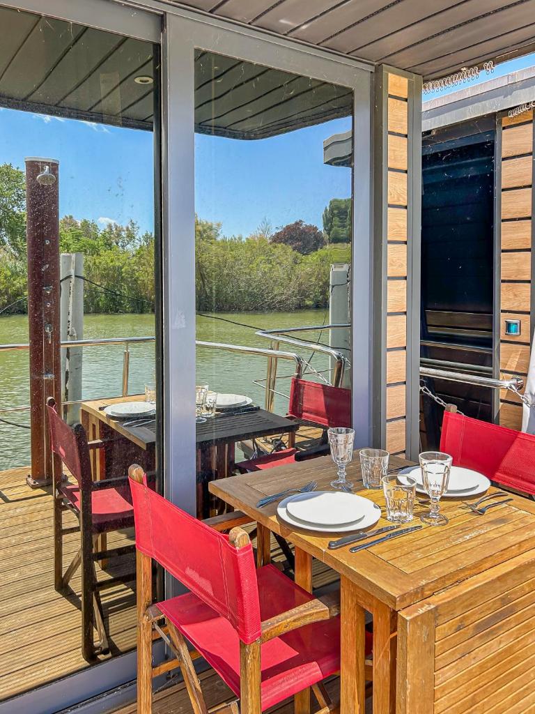 une terrasse avec une table et des chaises sur un bateau dans l'établissement Séjour Unique sur un Bateau "Marius", à Vauvert