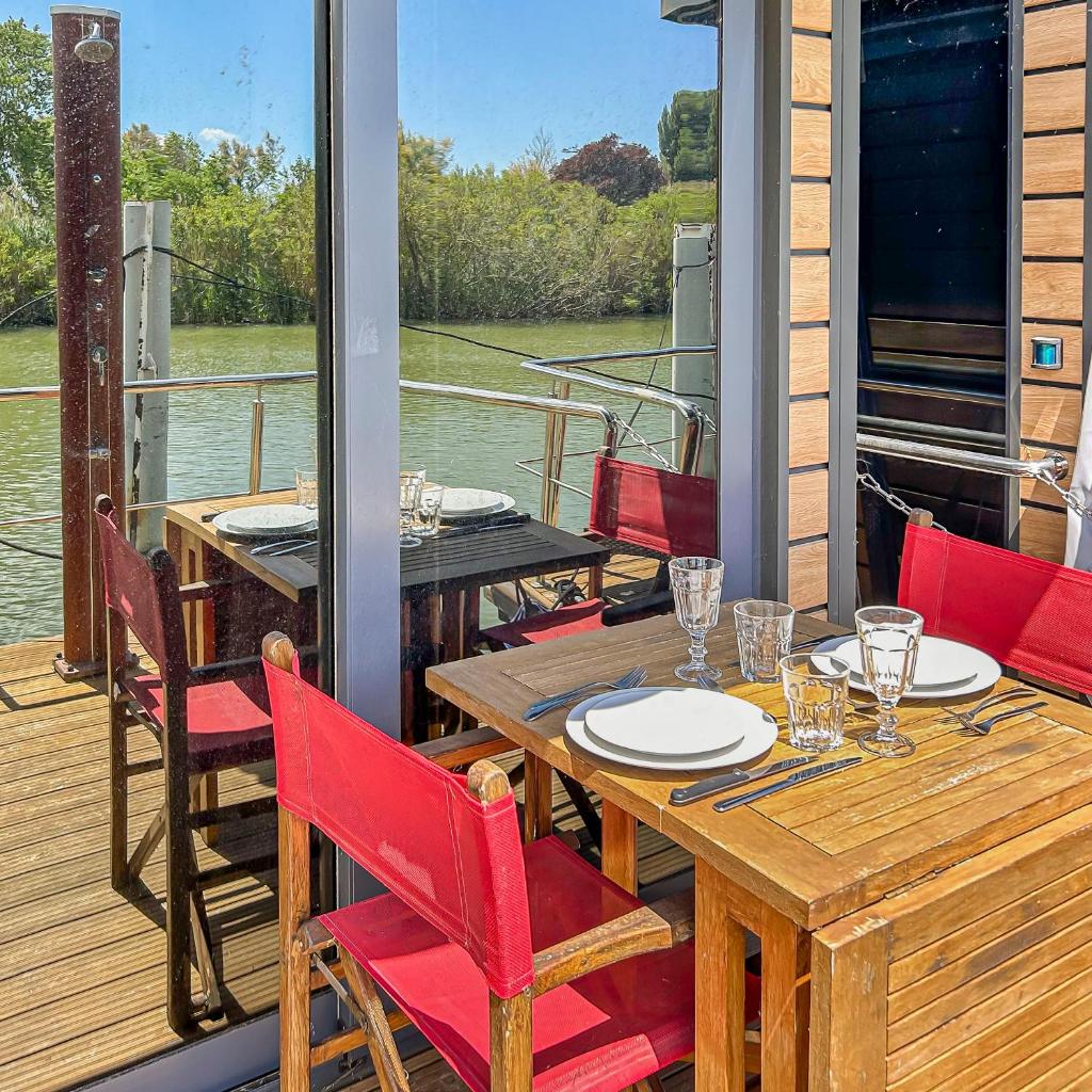 un porche avec une table et des chaises en bois sur un bateau dans l'établissement Séjour Unique sur un Bateau "Marius", à Vauvert