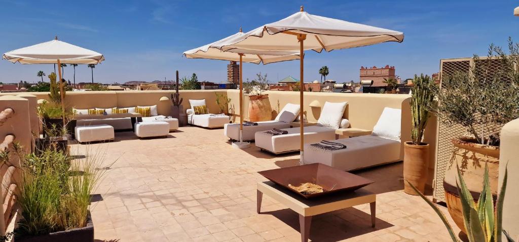 un patio avec des canapés et des parasols sur le toit dans l'établissement Riad de Vincent, à Marrakech