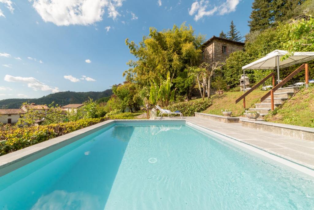 une piscine bleue avec une colline en arrière-plan dans l'établissement Villa Raffaelli, à Fosciandora