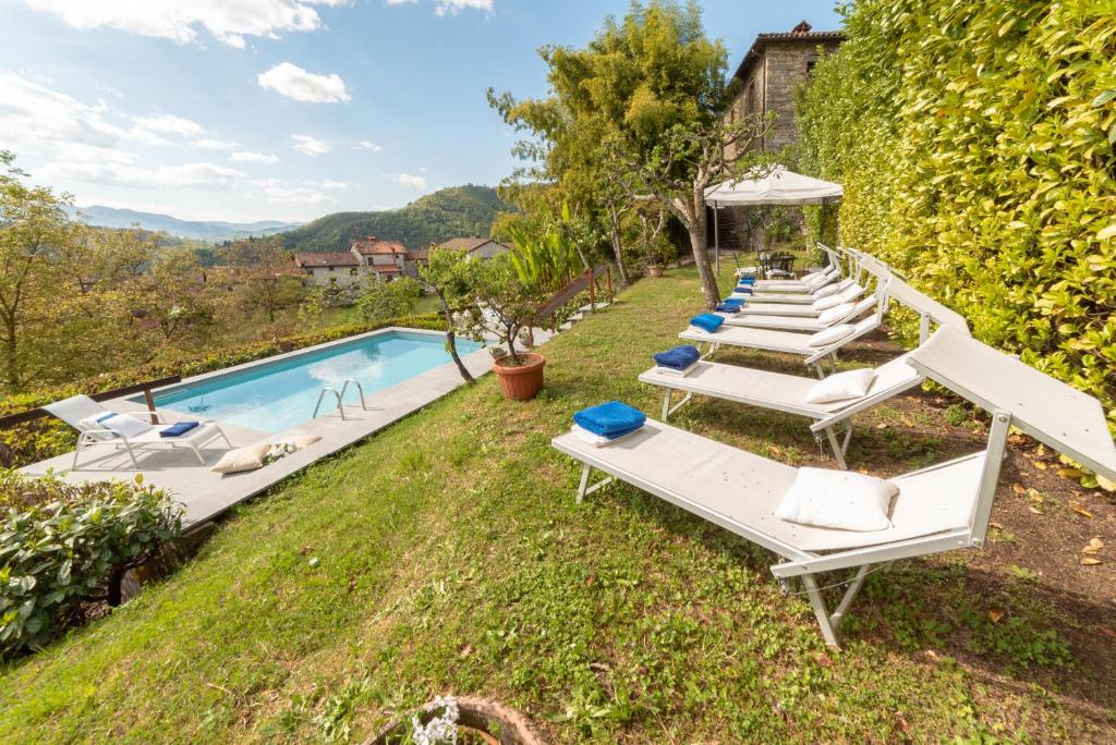 une rangée de chaises longues à côté d'une piscine dans l'établissement Villa Raffaelli, à Fosciandora