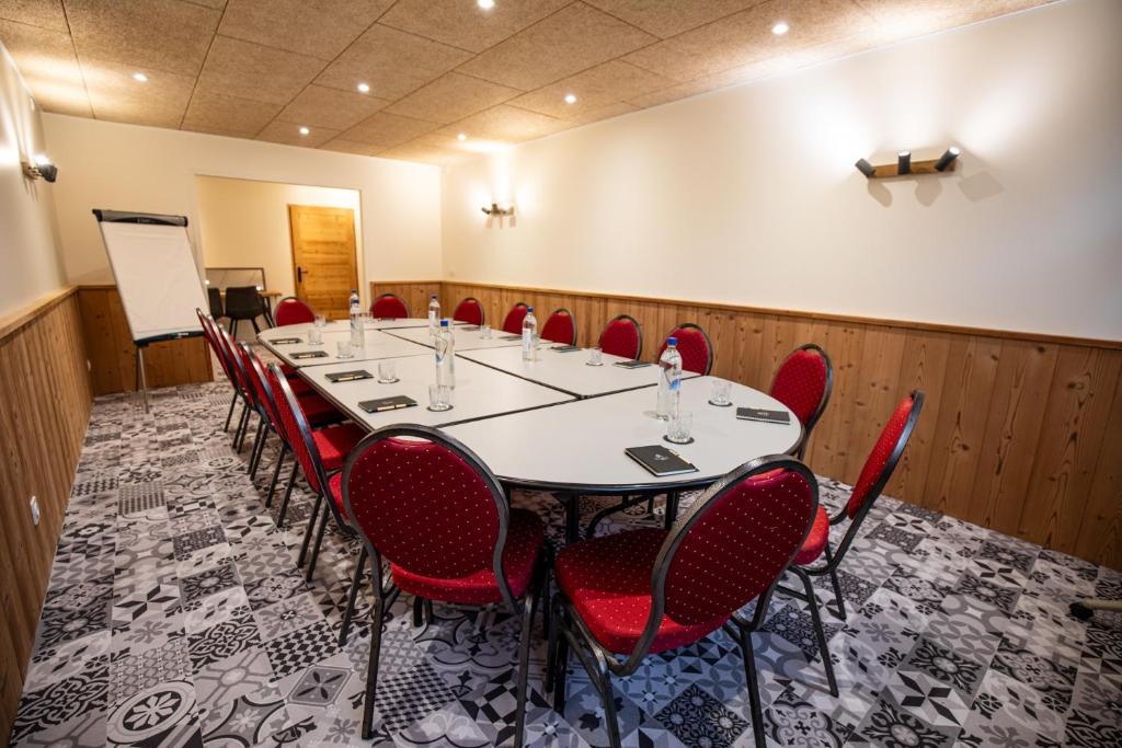 une salle de conférence avec une longue table et des chaises rouges dans l'établissement Logis Le Vernay, à Autrans