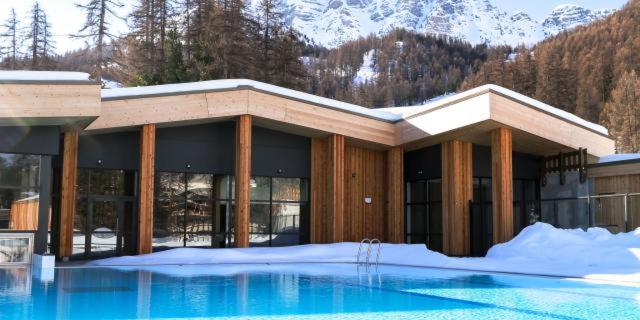 un bâtiment avec une piscine dans la neige dans l'établissement Vars, Appart spacieux rénové 4 couchages dans chalet, à Vars