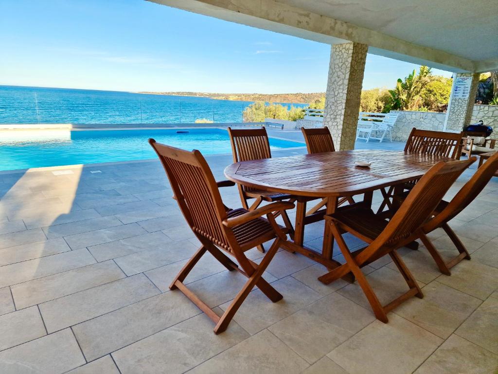 une table et des chaises en bois sur une terrasse dans l'établissement Villa Daniela - Villa con piscina privata e discesa a mare tra Catania e Siracusa, à Augusta