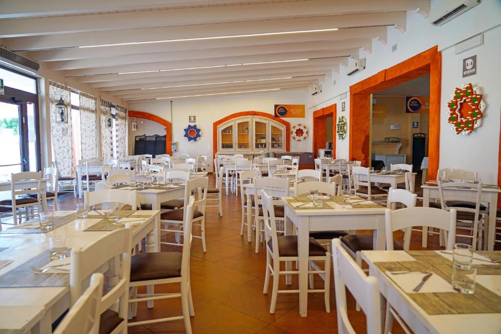 une salle à manger avec des tables et des chaises blanches dans l'établissement Chiusurelle Village Resort, à Punta Prosciutto