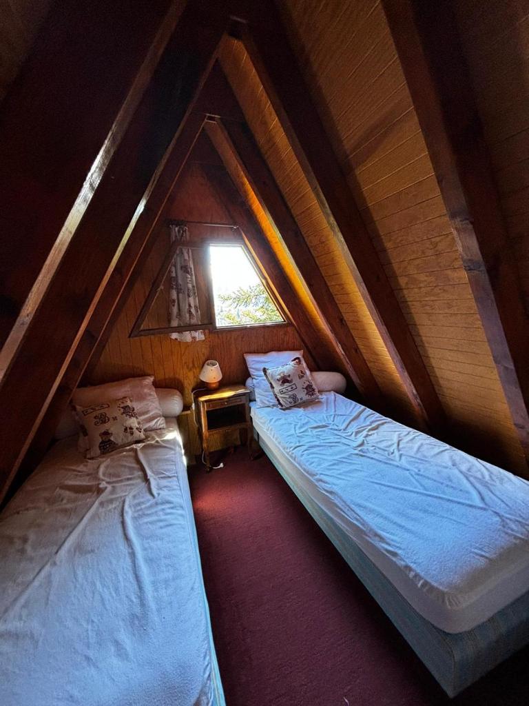 deux lits dans une chambre mansardée avec une fenêtre dans l'établissement Chalet de montagne, à Ustou