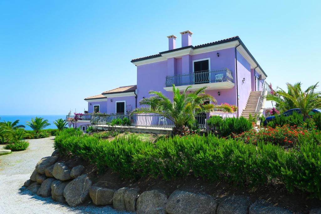 une maison violette sur la plage à côté de l'océan dans l'établissement Villaggio Hotel Lido San Giuseppe, à Briatico