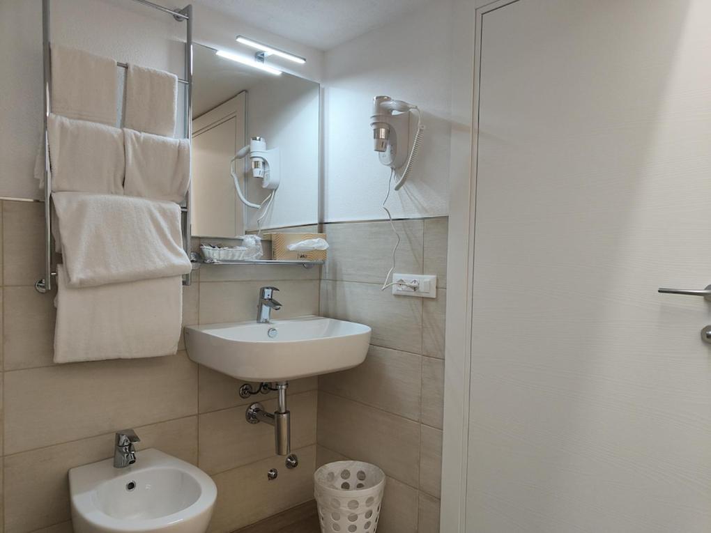 une salle de bain blanche avec un lavabo et un miroir dans l'établissement Hotel Anna, à Fetovaia