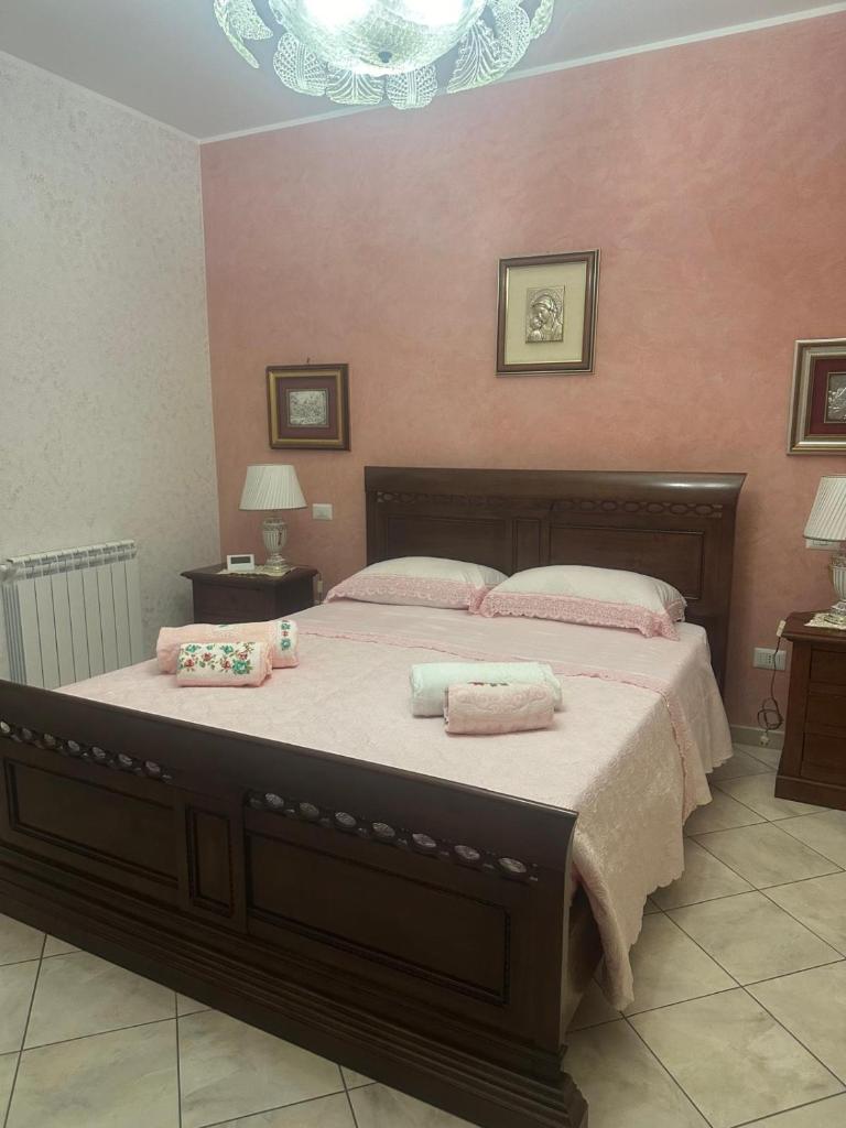 - une chambre avec un grand lit aux murs roses dans l'établissement Villa Framaca, à Furnari