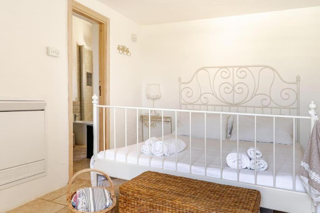 une chambre blanche avec un lit avec des serviettes dessus dans l'établissement Trullo Vittoria Ostuni with private swimming pool, à Ostuni