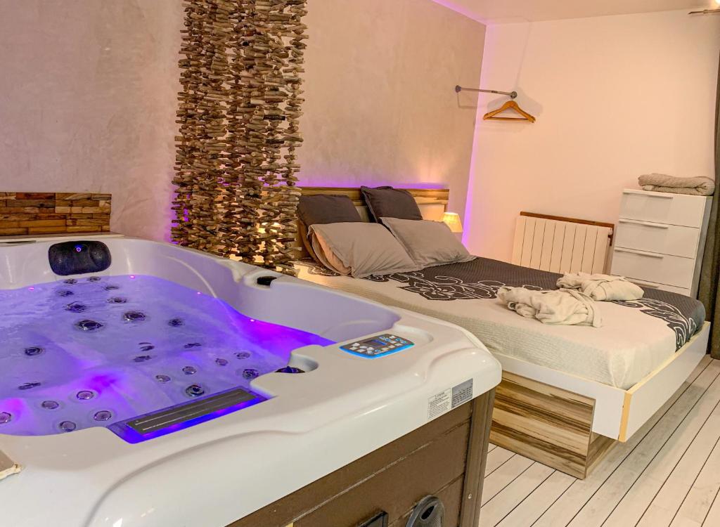 une chambre avec une grande baignoire à côté d'un lit dans l'établissement Domaine de la Besnerie Gites avec SPA Privatif à 10 min du Mont St Michel, à Tanis