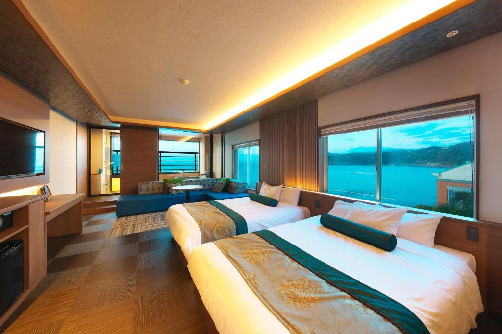 une chambre d'hôtel avec deux lits et une grande fenêtre dans l'établissement Senoumi, à Higashiizu