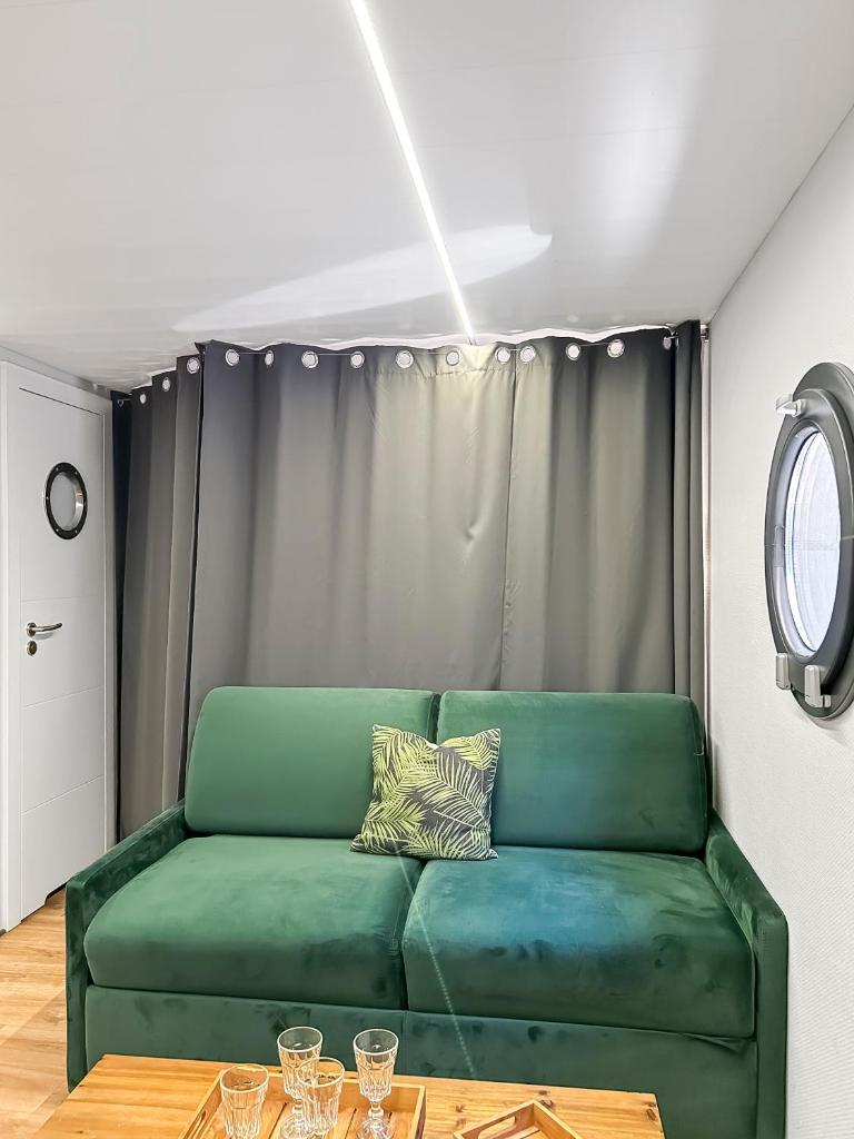 un canapé vert dans un salon avec une table dans l'établissement Bord du Canal du Rhône à Sète sur "César", à Vauvert