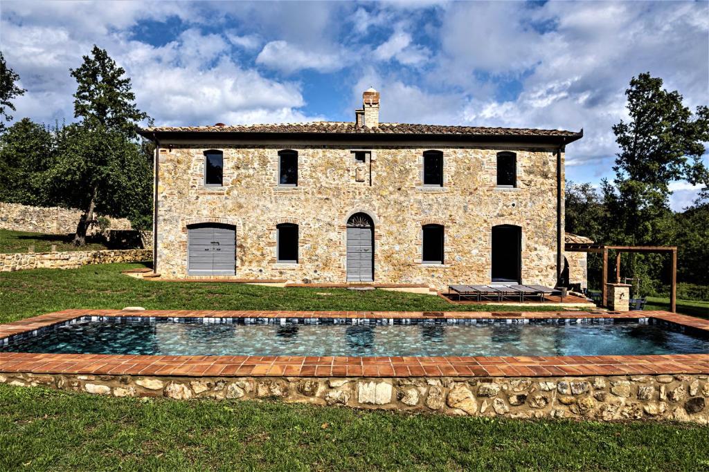 une maison en pierre avec une piscine en face de celle-ci dans l'établissement Tenuta San Galgano, à Monticiano