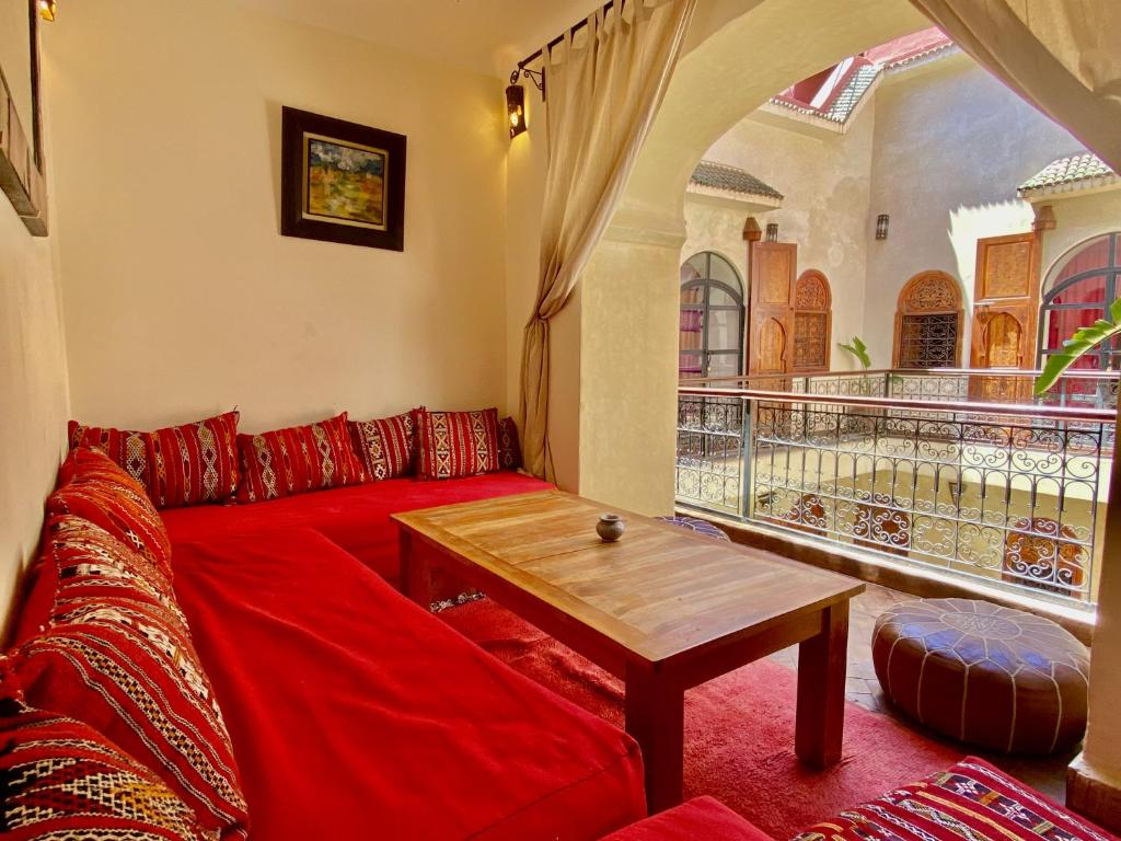 un salon avec un canapé rouge et une table dans l'établissement Riad Prada, à Marrakech