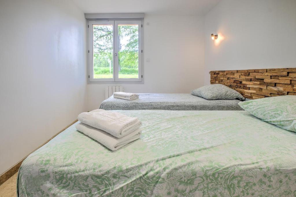 deux lits jumeaux dans une chambre avec fenêtre dans l'établissement Gite Deodatus avec piscine, à Cladech 23 autres photos